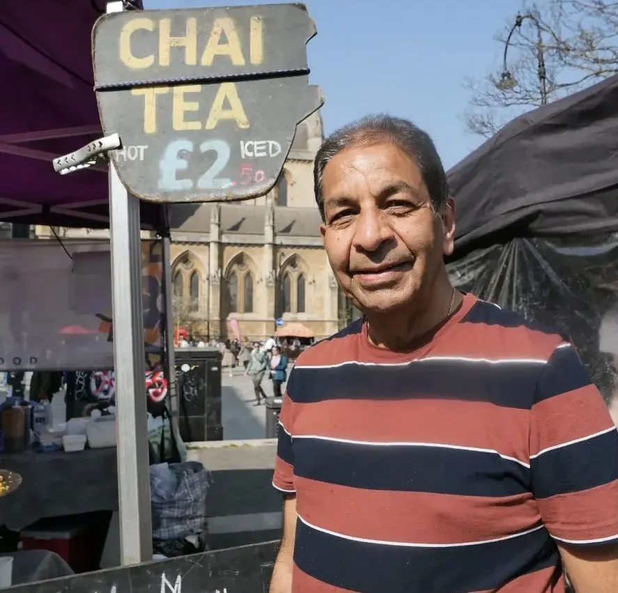 Dad standing beside the Mumbai Mix chai tea sign at the market stall