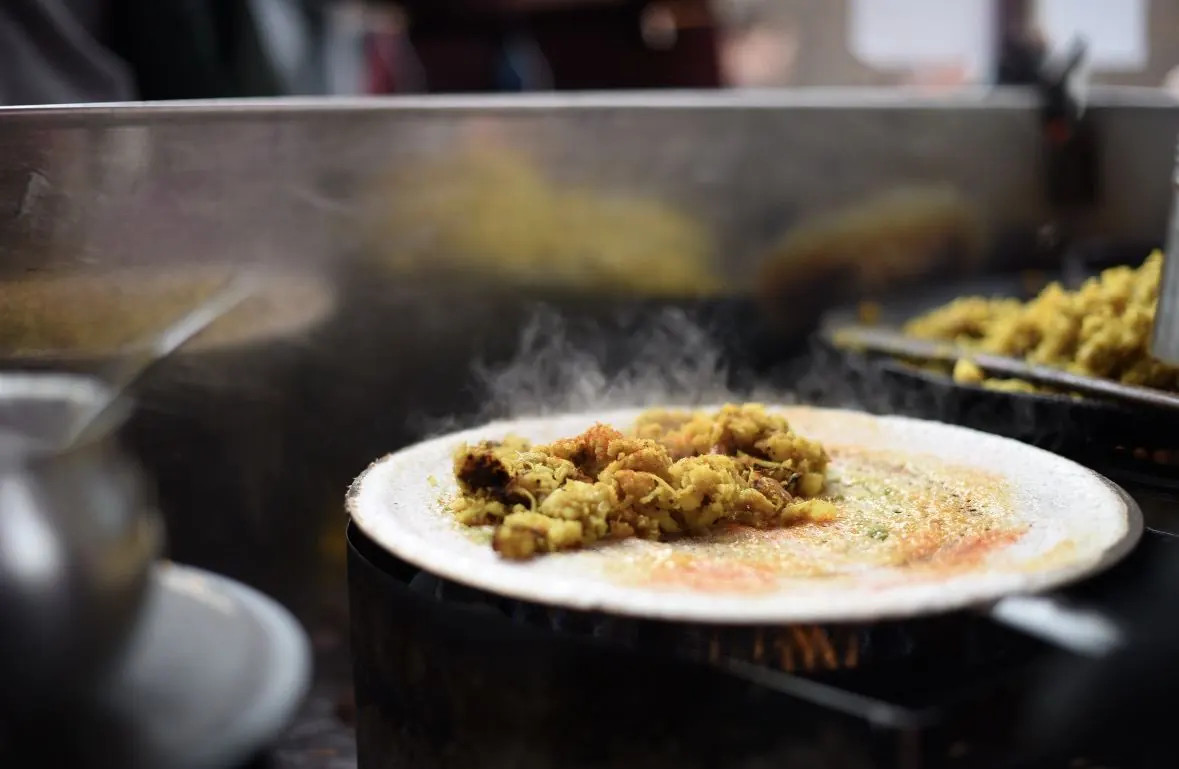 Dosa batter freshly spread thin across a hot tawa, ready to cook
