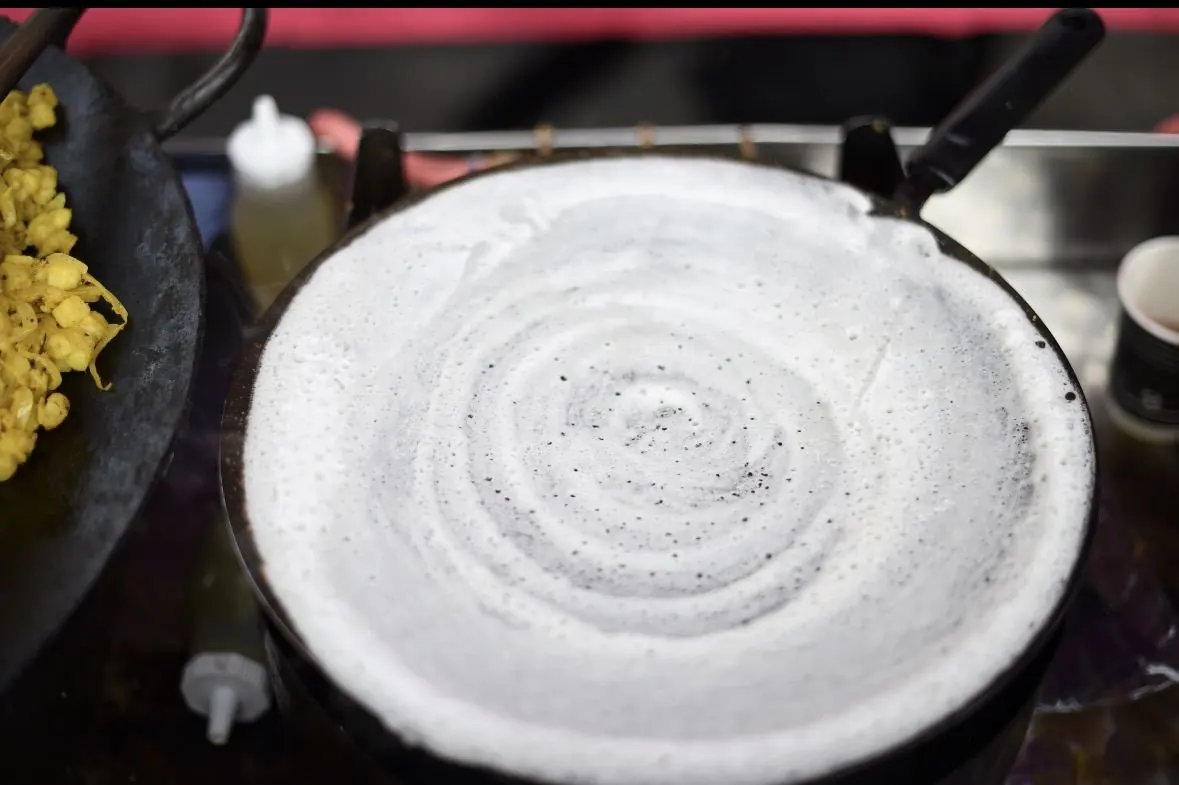 A dosa steaming on the tawa with a spiced potato filling added